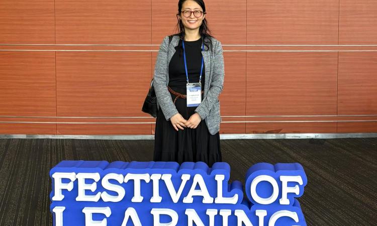 Jonna Lee standing behind a sign that reads "Festival of Learning"