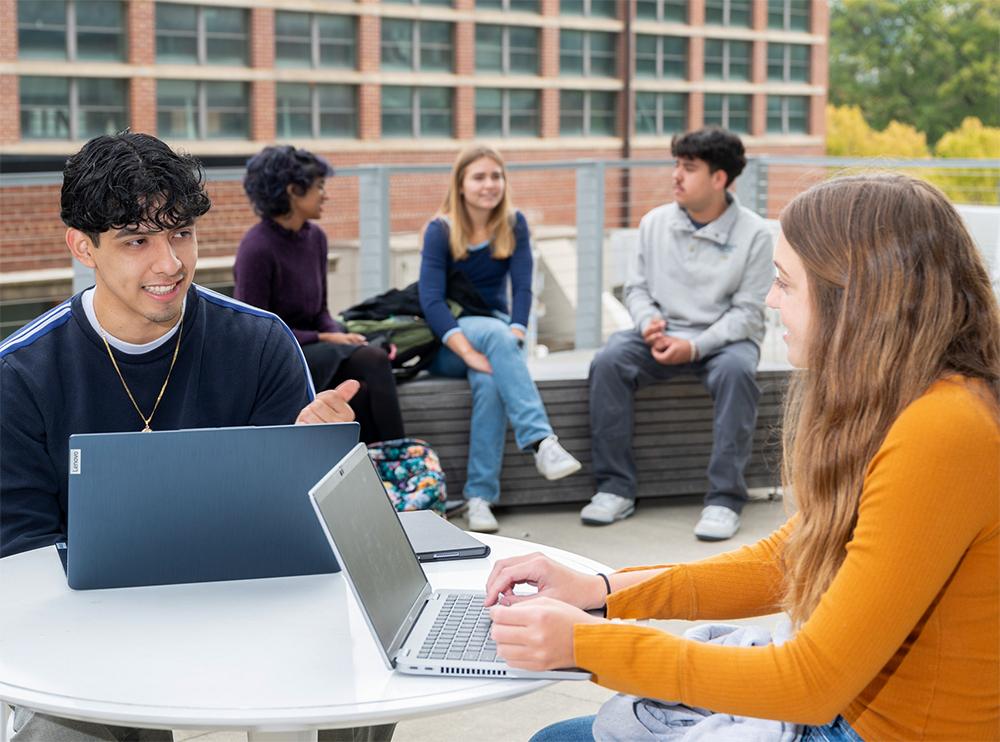 Students using laptop computers and talking.